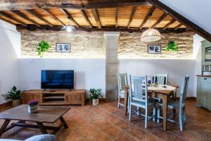 a living room with a table and chairs and a television at Casa do Cesteiro in Santiago de Compostela