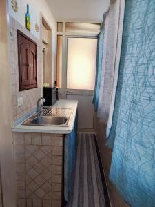 uma pequena cozinha com um lavatório e uma janela em Trapani love em Trapani
