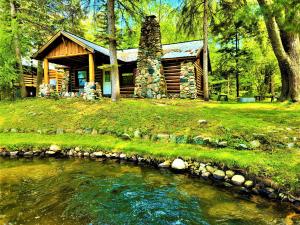 a log cabin with a stream in front of it at Steps to Beach-Hot Tub-Fireplace-Northern Original in Traverse City