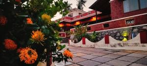 a building with orange flowers in front of a sidewalk at The Ixora - A Boutique Homestay in Varkala
