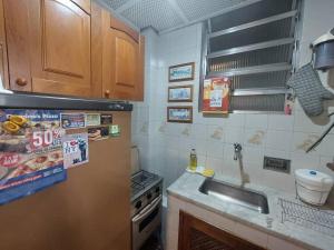 a kitchen with a sink and a refrigerator at Quarto e sala no melhor ponto de Ipanema in Rio de Janeiro