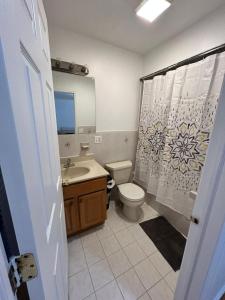 a bathroom with a toilet sink and a shower curtain at Bright & Spacious 3-Bed Close to NYC in Jersey City