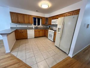 a kitchen with white appliances and wooden cabinets at Bright & Spacious 3-Bed Close to NYC in Jersey City