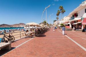 personas caminando por una acera de ladrillo cerca de la playa en Hotel Kasa, en Las Palmas de Gran Canaria