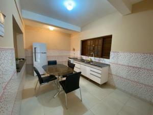 a kitchen with a table and chairs and a refrigerator at Casa Família com ar Vaga Praia do Centro Paraty in Paraty