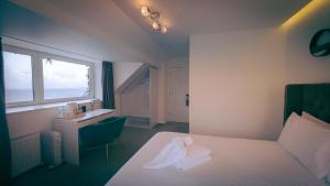 a bedroom with a bed and a desk and a window at OYO Newquay Beach Hotel in Newquay