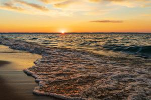 a sunset on a beach with the ocean at Creekside Hot Tub-Walk to Beach-Uniquely Northern in Traverse City