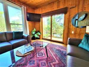 uma sala de estar com um sofá e uma mesa de vidro em Creekside Hot Tub-Walk to Beach-Uniquely Northern em Traverse City