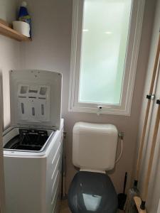 una pequeña cocina con aseo y ventana en Mobil home Aventura 6-8 personnes tout confort en Saint-Brevin-les-Pins