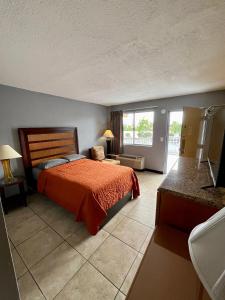 a bedroom with a bed with a orange bedspread at Budget Inn in Punta Gorda