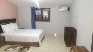 a white bedroom with a bed and a window at Auberge Mandar itto A station de service ZIZ in Aït nʼTaleb Akka