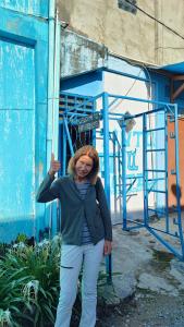 a woman standing in front of a blue building at Pintu Biru Hostel in Wamena