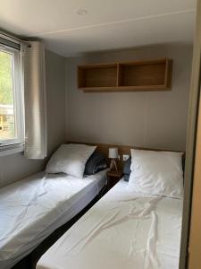 2 camas en una habitación pequeña con ventana en Mobil home Aventura 6-8 personnes tout confort en Saint-Brevin-les-Pins