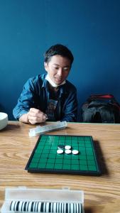 a man sitting at a table in front of a green board at Pintu Biru Hostel in Wamena