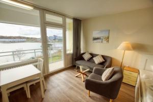 - un salon avec un canapé, une chaise et une fenêtre dans l'établissement Strandhotel, App 1SH308, à Heiligenhafen