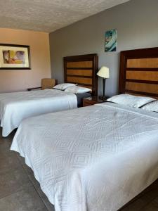 two beds in a hotel room with white sheets at Budget Inn in Punta Gorda