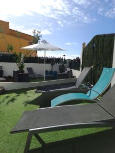 a patio with chairs and an umbrella and grass at Lovely new House - Guests Apartments in Olhão