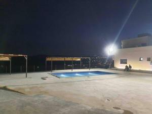 Breeze House في Kafr Khall: حمام سباحة في موقف للسيارات في الليل