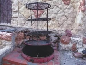 a fire pit with a grill in front of a stone wall at Breeze House in Kafr Khall