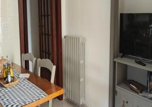 a dining room table with a radiator and a television at Domus Parva, appartamento con giardino in Pompei