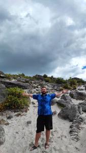a man standing on a beach with his arms outstretched at Pintu Biru Hostel in Wamena