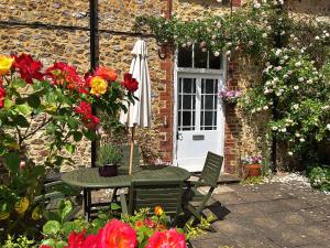 een tafel met een parasol in een tuin met bloemen bij Finest Retreats - The Coach House at Holyford Farm in Colyford