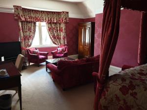 1 dormitorio con paredes rosas, 1 cama y sillas en Mansion House Hotel, en Elgin