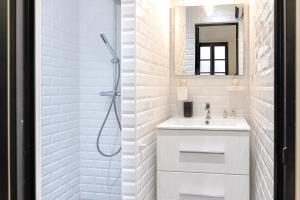 y baño blanco con lavabo y ducha. en Superbe maison au coeur de la ville à deux pas de la Côte des Basques en Biarritz