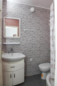a bathroom with a sink and a mirror and a toilet at Guest House Tanja in Orebić