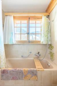 y baño con bañera y ventana. en Villars Alpine Heaven - Ski In, en Villars-sur-Ollon