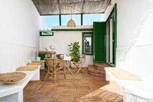 un patio con persianas verdes, mesa y sillas en Villa Carolina - jardín independiente, recién reformada. en Maspalomas