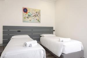 two beds in a room with white sheets at Melissa Suite in Casalecchio di Reno