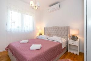 a bedroom with a pink bed with two towels on it at Apartment APARTMAN MIA in Brodarica