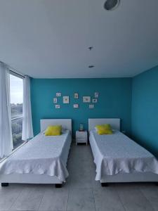 2 camas en una habitación con paredes azules en Apartamento de playa con vista al mar en coronado en Playa Coronado