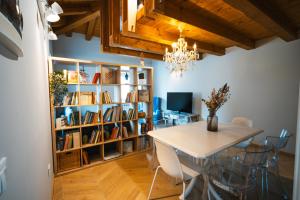 une salle à manger avec une table et une étagère à livres dans l'établissement Le Finestre Apartments Muggia, à Muggia