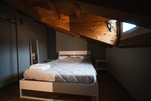 un letto in una camera da letto con soffitto in legno di Le Finestre Apartments Muggia a Múggia