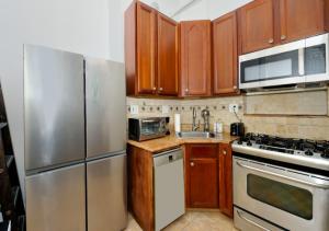 a kitchen with wooden cabinets and stainless steel appliances at Designer Three Bd Apartment In NYC in New York