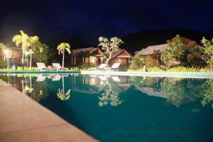 una piscina con una casa y un complejo en Pai Do See Resort - ปาย ดูร์ ซี รีสอร์ท, en Pai