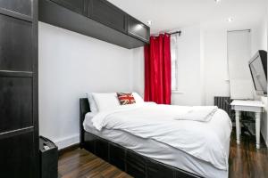 a bedroom with a large bed with a red curtain at Stylish 2 bedroom apartment in Shoreditch - London in London