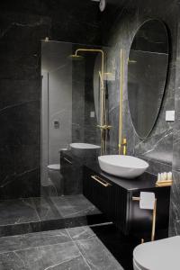 a black bathroom with a sink and a mirror at Srebrna Luxury Apartments - willa fabrykancka in Łódź