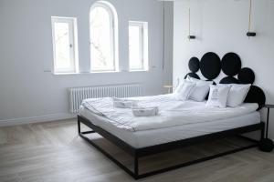 a white bedroom with a large bed with a black headboard at Srebrna Luxury Apartments - willa fabrykancka in Łódź