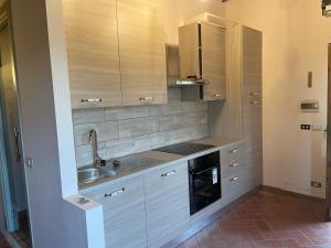 una cocina con armarios de madera y fregadero en Villino Glicine, en Buti