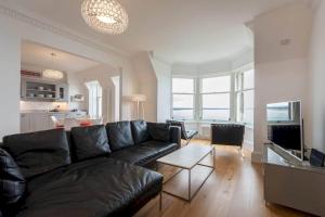 een woonkamer met een zwarte bank en een tafel bij Luxury Penthouse on The Scores - Best View in St Andrews in St Andrews