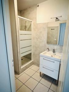 een badkamer met een wastafel en een spiegel bij Le chant des vagues in Frontignan