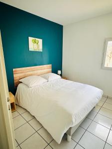 una camera con un grande letto con una parete blu di Le chant des vagues a Frontignan