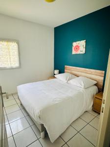 een slaapkamer met een groot wit bed en een blauwe muur bij Le chant des vagues in Frontignan