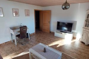 ein Wohnzimmer mit einem TV, einem Schreibtisch und einem Tisch in der Unterkunft House of Haiger Ferienwohnung mit Charme in Haiger