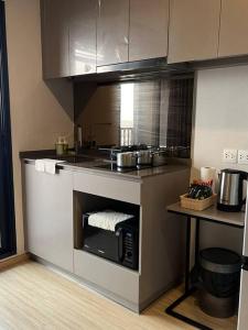 a kitchen with a stove and a microwave at The Cozy, 3 min walk to MRT, 2 STN to Royal Palace in Bangkok Yai