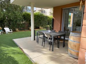 d'une terrasse avec une table, des chaises et un tonneau. dans l'établissement les Jardins du Ventoux, à Carpentras