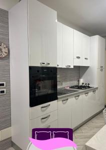 una cocina con armarios blancos y horno negro en B&B ANASTASIA, en Pompeya